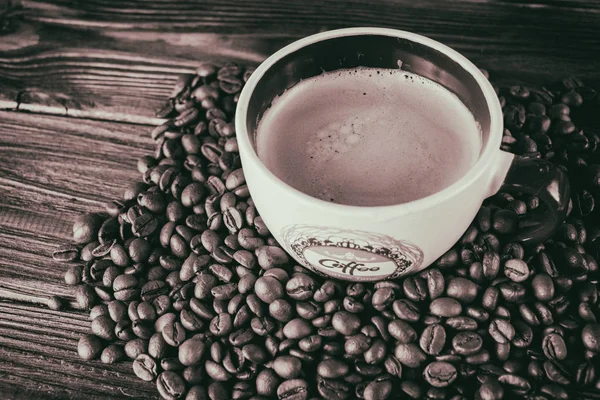 Taza de café y granos de café sobre un fondo de madera — Foto de Stock