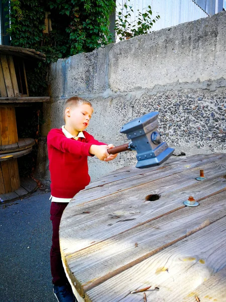 El chico golpea la mesa con un martillo — Foto de Stock