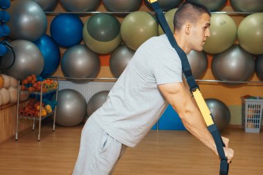 Genç adam bir spor salonunda trx devreye girer
