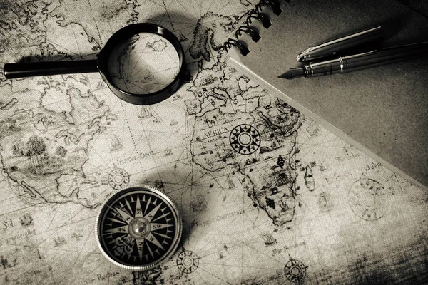 Un mapa antiguo, una brújula y una lupa — Foto de Stock