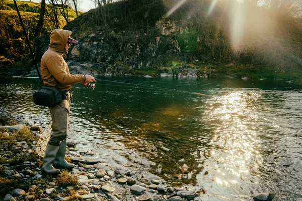 Pêcheur attrape une truite sur une rivière de montagne — Photo