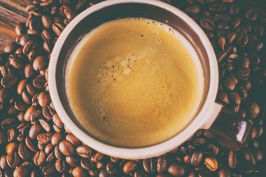 Tahta arka planda bir fincan kahve ve kahve çekirdeği.