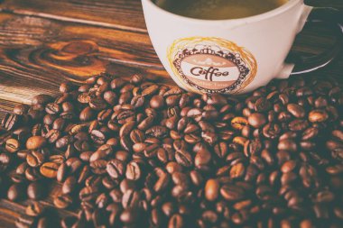 Tahta arka planda bir fincan kahve ve kahve çekirdeği.