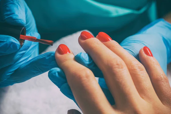 Maestro di manicure dipinge unghie in rosso — Foto Stock