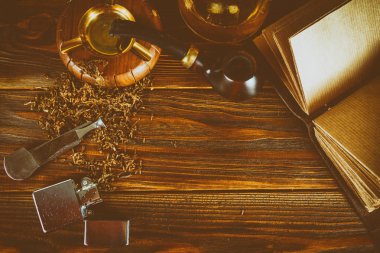 kahverengi bir masada bir sigara pipo, tütün, bir çakmak, bir viski, 