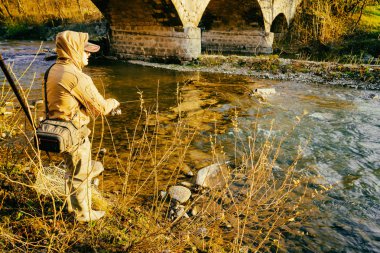 Balıkçı bir alabalık bir dağ nehir üzerinde yakalar.