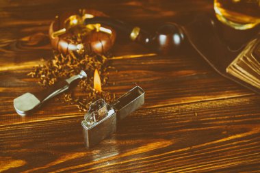 kahverengi bir masada bir sigara pipo, tütün, bir çakmak, bir viski, 