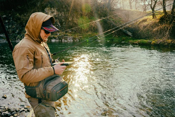 Pescador pega uma truta em um rio de montanha — Fotografia de Stock