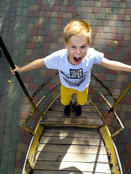 The boy is riding on a swing-boat — Stock Photo, Image