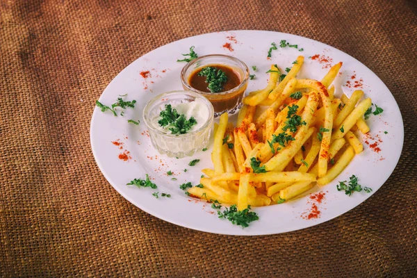 Batatas fritas em um prato com molhos — Fotografia de Stock