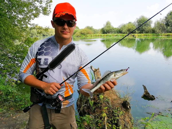 Pescador pegou um peixe segurando em sua mão — Fotografia de Stock