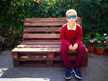 şık çocuk ahşap bir bankta oturur