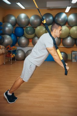 Genç adam bir spor salonunda trx devreye girer