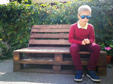 şık çocuk ahşap bir bankta oturur