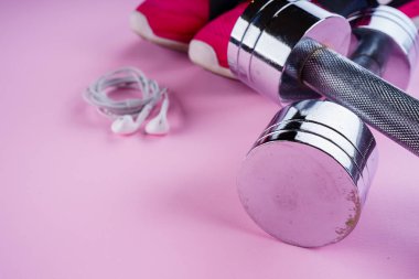 spor konsepti: spor ayakkabıları, halter, pembe backgr kulaklık