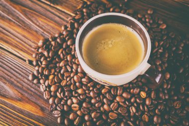 Tahta arka planda bir fincan kahve ve kahve çekirdeği.