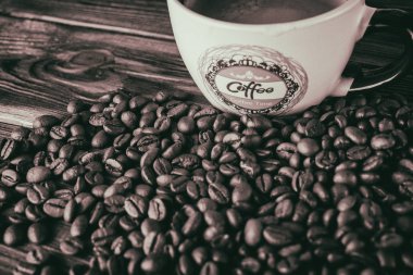 Tahta arka planda bir fincan kahve ve kahve çekirdeği.