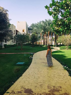 Kız tatil köyünde yol boyunca yürüyor.