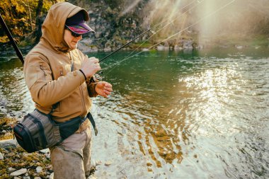 Balıkçı bir alabalık bir dağ nehir üzerinde yakalar.