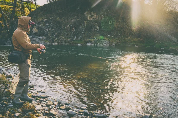 Pescador atrapa una trucha en un río de montaña — Foto de Stock