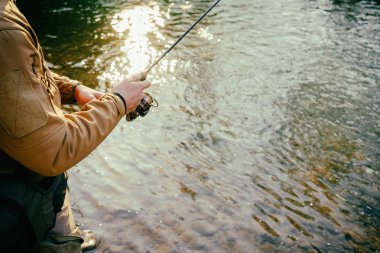 Balıkçı bir alabalık bir dağ nehir üzerinde yakalar.