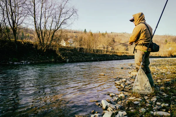 Pescador atrapa una trucha en un río de montaña — Foto de Stock