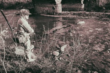 Balıkçı bir alabalık bir dağ nehir üzerinde yakalar.