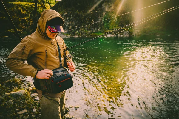 Fisherman catches a trout on a mountain river — Stock Photo, Image