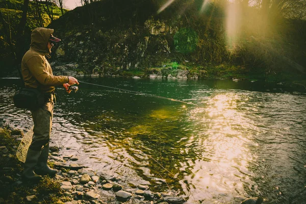 Pescatore cattura una trota su un fiume di montagna — Foto Stock