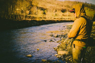 Balıkçı bir alabalık bir dağ nehir üzerinde yakalar.