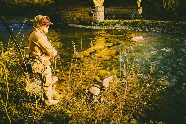 Pescador atrapa una trucha en un río de montaña — Foto de Stock