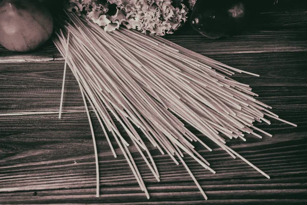 Spaghetti and vegetables on a wooden background — Stock Photo, Image