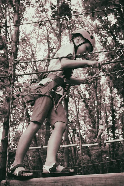 Le garçon grimpe dans un parc suspendu — Photo