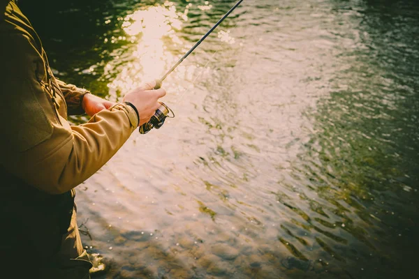 Pescador atrapa una trucha en un río de montaña — Foto de Stock