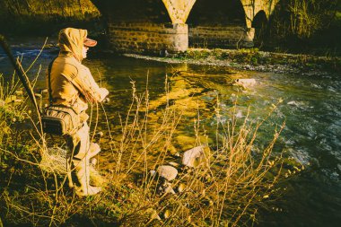 Balıkçı bir alabalık bir dağ nehir üzerinde yakalar.