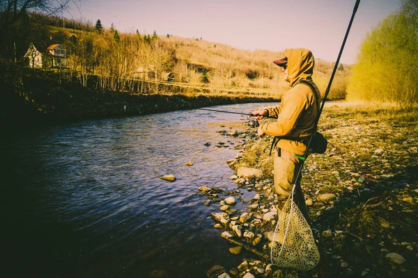 Pescador atrapa una trucha en un río de montaña — Foto de Stock