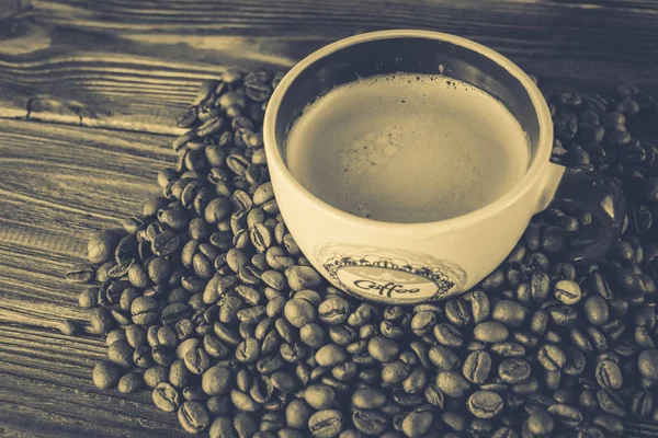 Taza de café y granos de café sobre un fondo de madera — Foto de Stock