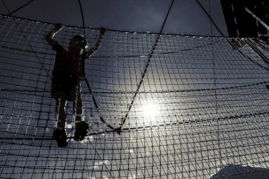 Çocuk ip parkında oynuyor.