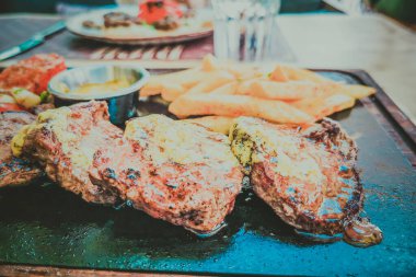 Biftek ve patates arka planda.