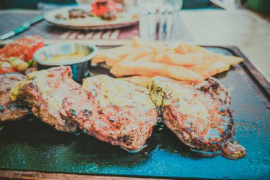 Biftek ve patates arka planda.