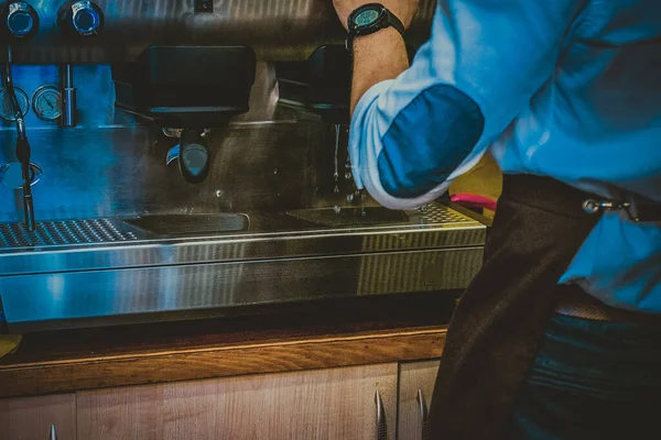 Barista makes coffee in a cafe background