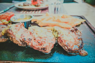 Biftek ve patates arka planda.