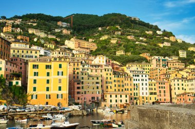 Colorful coastal town with fishing boats and yachts in harbor on Mediterranean coast.