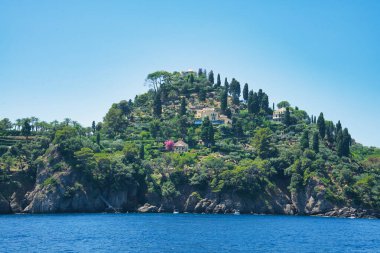 İtalya 'nın Ligurian kıyısındaki mavi Akdeniz üzerinde yeşil tepeleri ve villaları olan Rocky sahili..