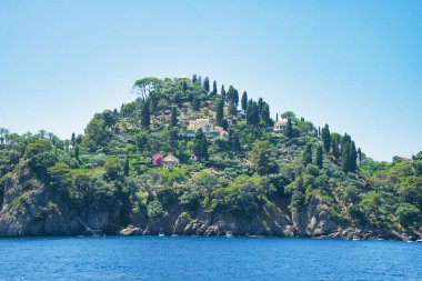 İtalya 'nın Ligurian kıyısındaki mavi Akdeniz üzerinde yeşil tepeleri ve villaları olan Rocky sahili..