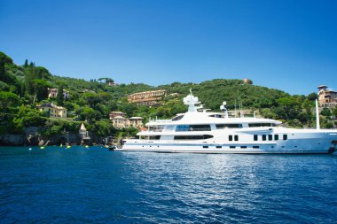 Harbor view of Portofino with sailing boats, yachts and the church of St. George on the hill in the background, Liguria, Italy.