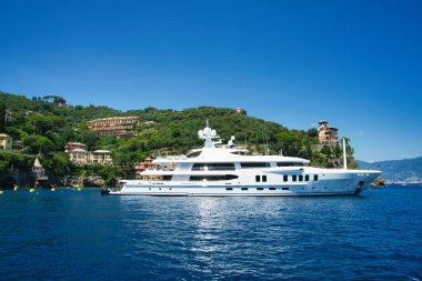 Harbor view of Portofino with sailing boats, yachts and the church of St. George on the hill in the background, Liguria, Italy.