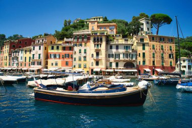 Harbor view of Portofino with sailing boats, yachts and the church of St. George on the hill in the background, Liguria, Italy.