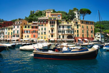 Harbor view of Portofino with sailing boats, yachts and the church of St. George on the hill in the background, Liguria, Italy.