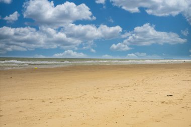 Sakin denizi ve bulutları olan boş kumlu sahil.
